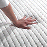 close up on hand touching top of mattress to feel texture and firmness