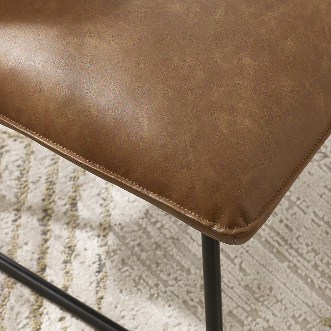 close up image of brown faux leather seat of brown lounge chair