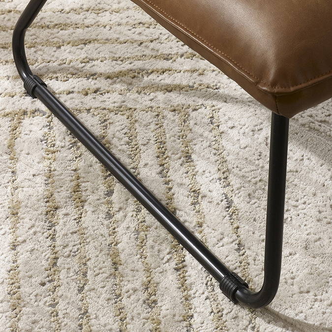 close up image of sleek black metal legs of brown faux leather accent chair