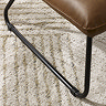 close up image of sleek black metal legs of brown faux leather accent chair