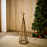 small wicker christmas tree with star and LED lighting woven through, stood on rug in living room in front of christmas spruce