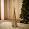 small wicker christmas tree with star and LED lighting woven through, stood on rug in living room in front of christmas spruce