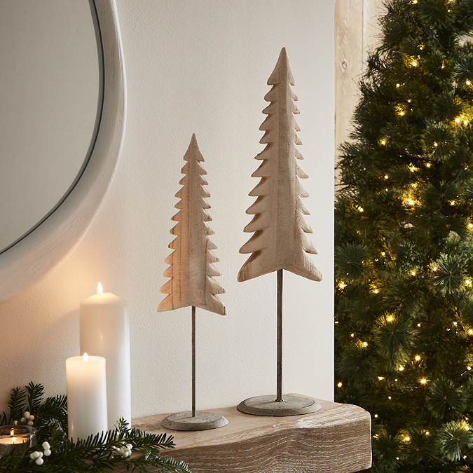 pair of whitewashed wooden tree decorations, one 53cm and the other 40cm tall, stood together at the end of a light oak mantlepiece.
