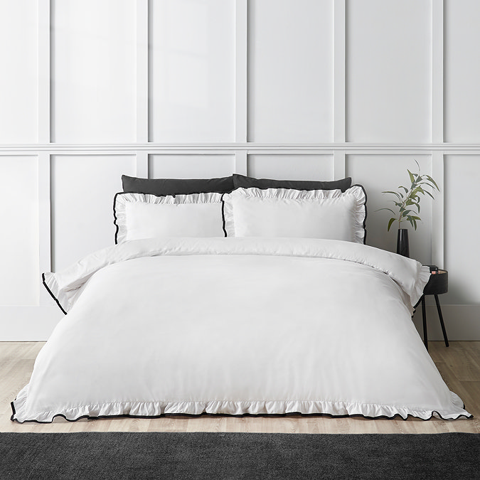 image of white bedding on a double bed edged with black frill