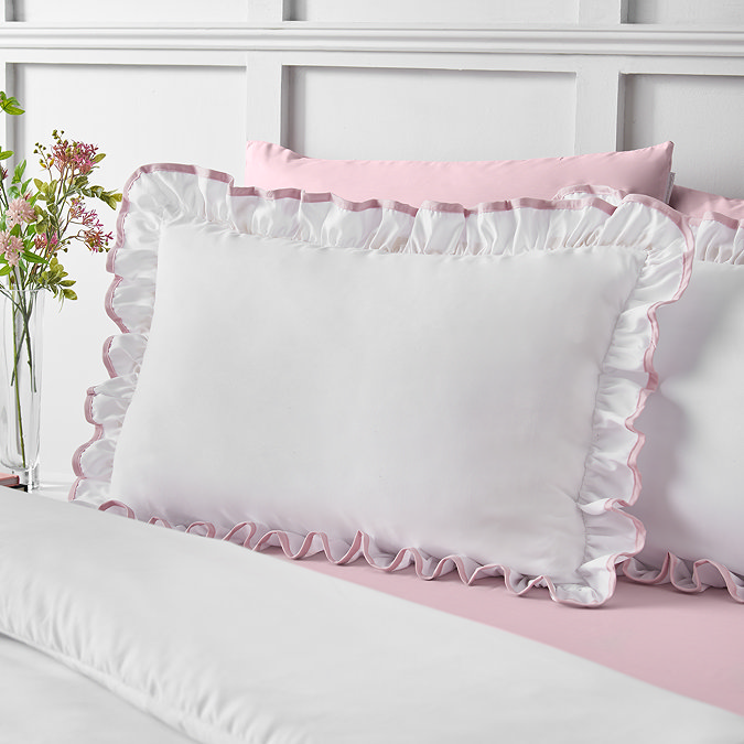 close up image of crisp white bedding with ruffle trim and pink contrast border