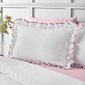 close up image of crisp white bedding with ruffle trim and pink contrast border