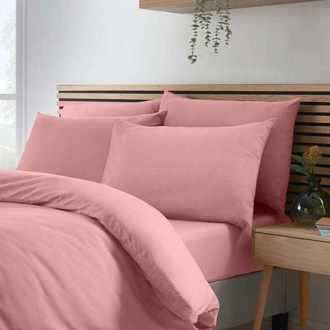 side-on image of coral pink duvet cover set, folded over slightly to show matching fitted sheet and pillowcases