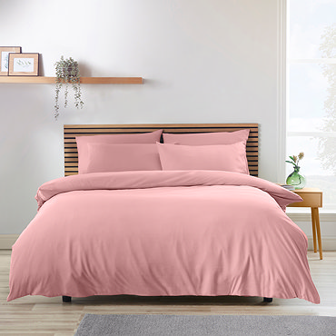 side-on image of coral pink duvet cover set, folded over slightly to show matching fitted sheet and pillowcases