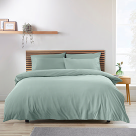 light green duvet cover set on a bed, with cream wall and light wood headboard