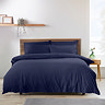 navy blue duvet cover set on a bed, in front of cream wall with nordic wood headrest