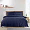 navy blue duvet cover set on a bed, in front of cream wall with nordic wood headrest