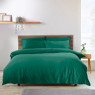 side-on image of teal green duvet cover set, slightly folded back to reveal matching fitted sheet and pillowcases