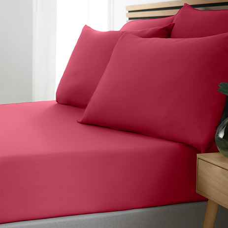 side-on image of bed with no duvet to show hot pink fitted sheet and matching pillowcases