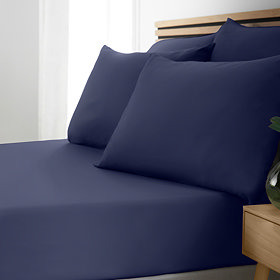 side-on image of bed with navy blue fitted sheet and matching pillowcases
