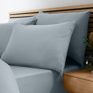 side-on image of bed with duvet cover folded over slightly to reveal slate grey-blue fitted sheet with matching pillowcase set