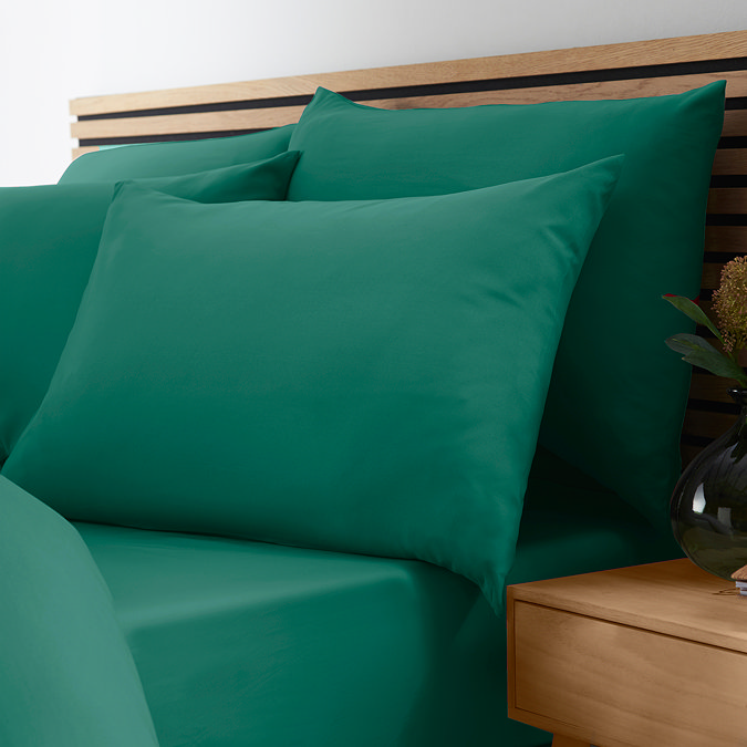 side-on close up image of bed with teal green fitted sheet and matching pillowcases
