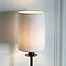close up on cylindrical fabric shade of wall light on cream wall