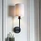 image of wall lamp with cylindrical fabric shade and matt black arm attached to a cream wall