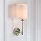 image of wall light with cylindrical fabric shade and nickel arm on cream wall