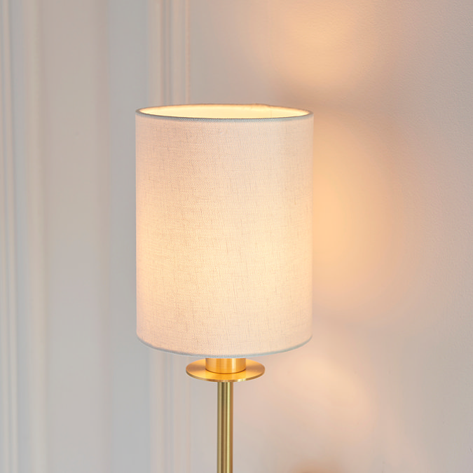 close up on cylindrical linen shade of satin brass wall light
