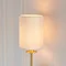 close up on cylindrical linen shade of satin brass wall light