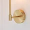 close up on satin brass arm of wall light on cream wall