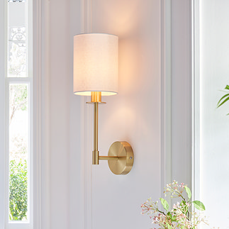 image of wall light with cylindrical fabric shade and satin brass arm on a cream wall