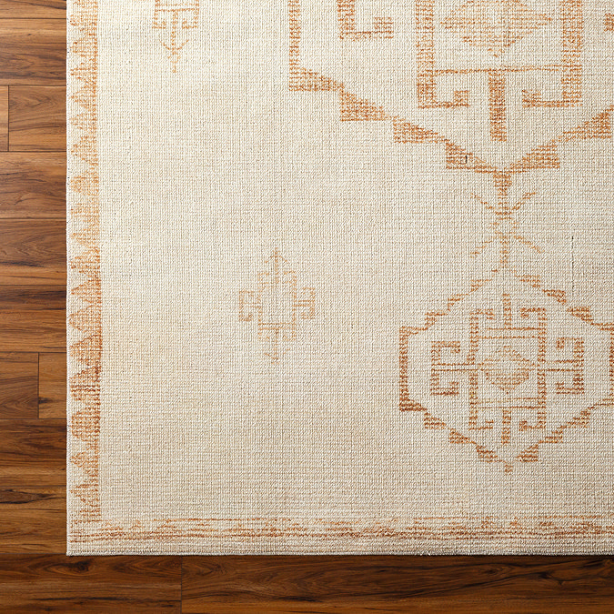 close up image of corner of ivory rug with burnt orange scandi pattern, focus on colour and texture