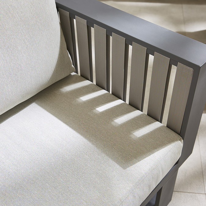 close up image of grey slatted outdoor armchair with plush cream cushion