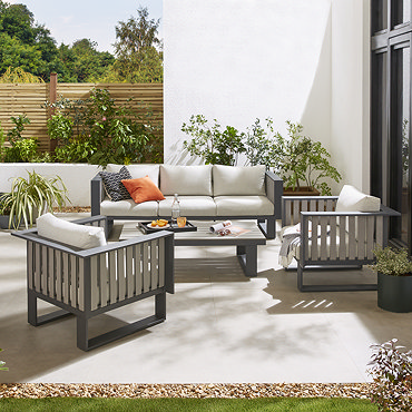 image taken from slightly above of modern slatted grey outdoor lounge set with cream cushions, on patio during a sunny day