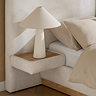 close up image of built-in fabric side table of upholstered double bed, with white lamp resting on it