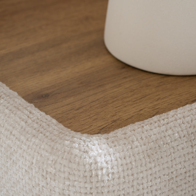 super close up zoomed in image of wood and fabric side table on bed