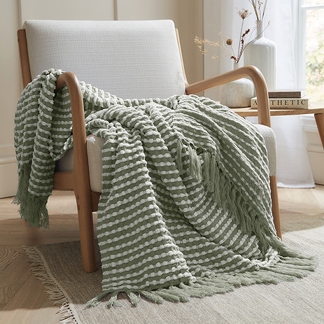sage green stab stitch throw draped over a chair