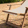 close up image of acacia wood frame of clay pink and white striped sun lounger