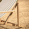 close up on side of clay pink and white deck chair with acacia wood folding frame