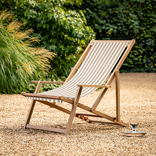 image of clay pink and white striped deckchair on sandy gravel of back garden