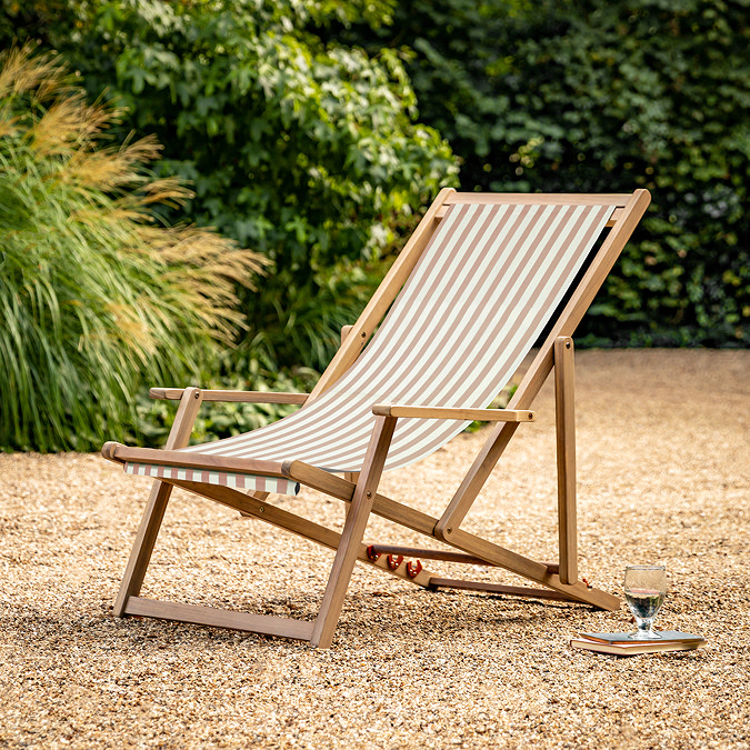 image of clay pink and white striped deckchair on sandy gravel of back garden
