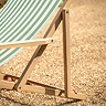 close up image of side of acacia wood deck chair with green and white stripes