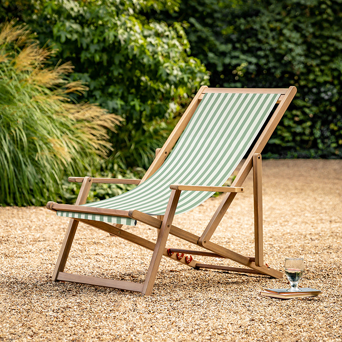 image of green and white stripe deckchair with acacia wood frame, on sandy gravel patio