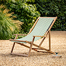 image of green and white stripe deckchair with acacia wood frame, on sandy gravel patio