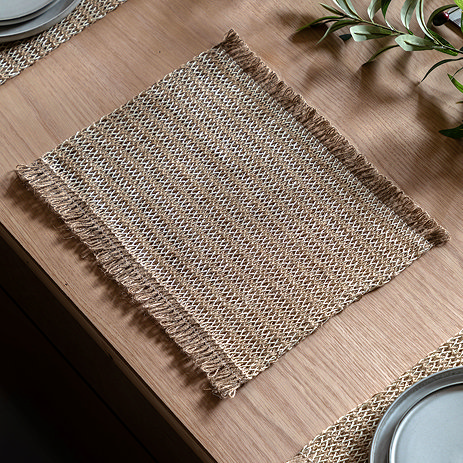 image of striped woven jute placemat with fringed top and bottom, on a light oak dining table