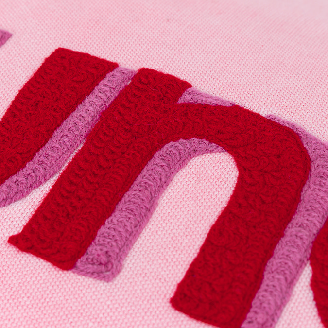 close up on dark pink woven word 'sunday' of light pink cushion