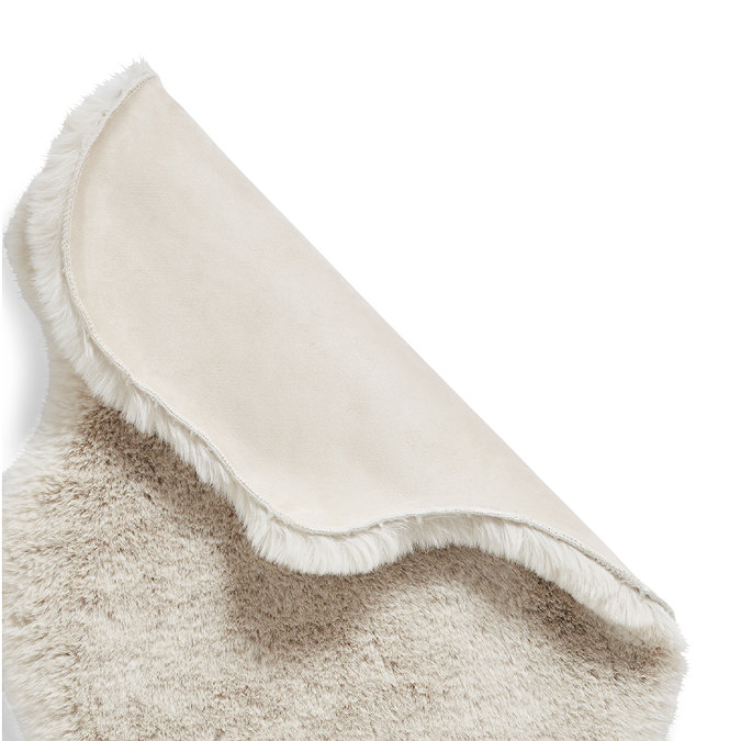 image of beige sheepskin rug folded over at the corner to reveal floor-facing material underneath