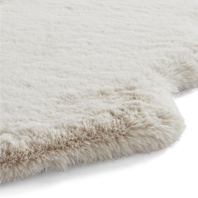 close up on side of beige sheepskin rug with wavy edges and soft pile