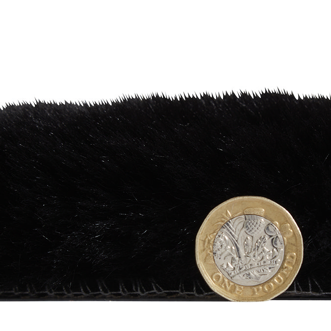 side-on image of faux sheepskin rug with pound coin stood up next to it to show rug as double the height of coin