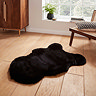 image of small black sheepskin rug on wooden flooring in front of window with light streaming through