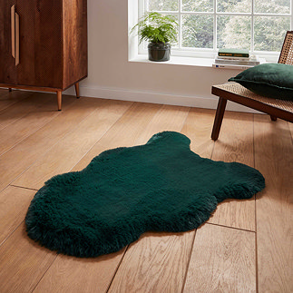 image of short dark green sheepskin rug with wavy edges on wooden flooring in front of window with natural light streaming through