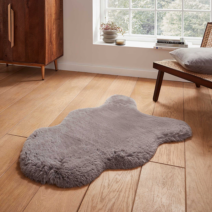 image of grey sheepskin rug with soft pile on wooden flooring in front of window with natural light streaming through