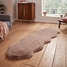 image of long mink brown sheepskin rug with wavy edges on wooden flooring in front of window with natural light streaming through