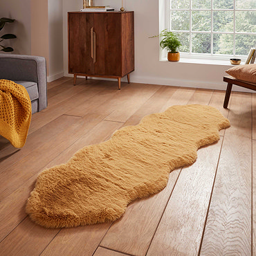 image of long mustard yellow sheepskin rug with wavy edges on wooden flooring in front of window with natural light streaming through